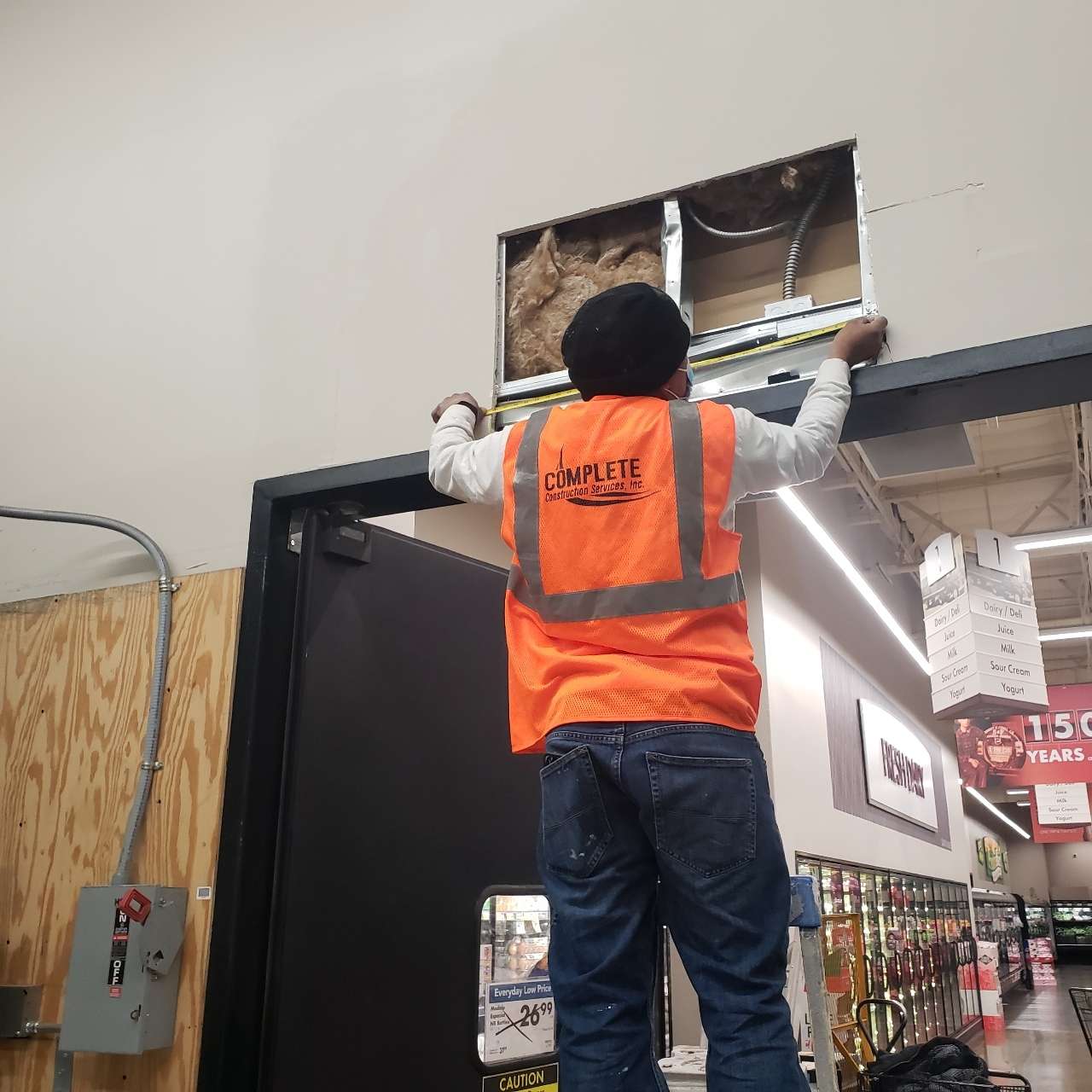 person fixing the signage above a grocery